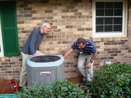 Buddy De Lozier (right), of Central, inspects a new heat pump with a homeowner participating in the pilot program. 