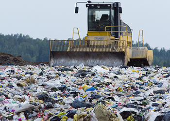 Bulldozer pushing trash in landfill