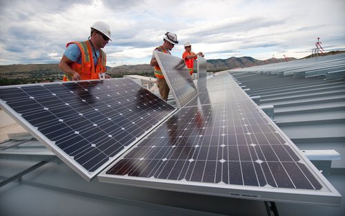 Installing solar panels on the roof of a research facility. Courtesy of DOE/NREL 